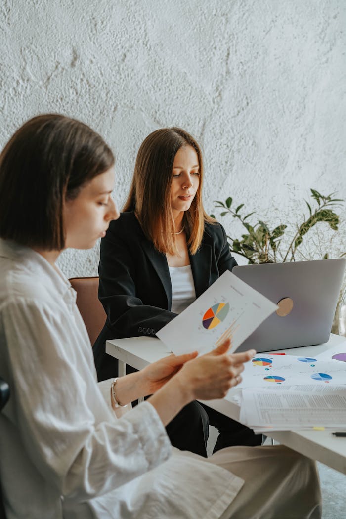Two women working with data charts and reports in a modern office environment.